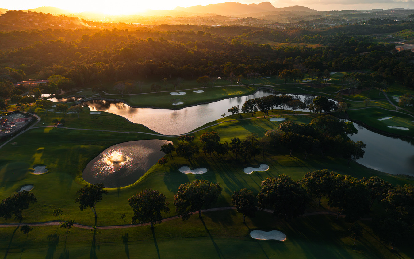Aerial view of a golf course at sunset with lakes catching the light