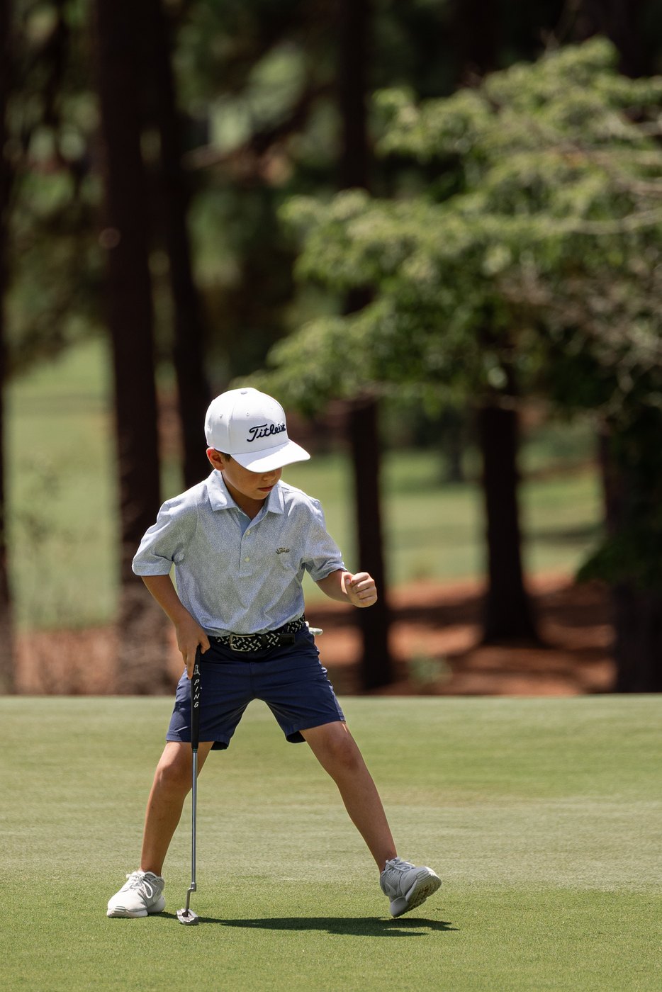 Junior golfer clenching both fists in celebration on the green