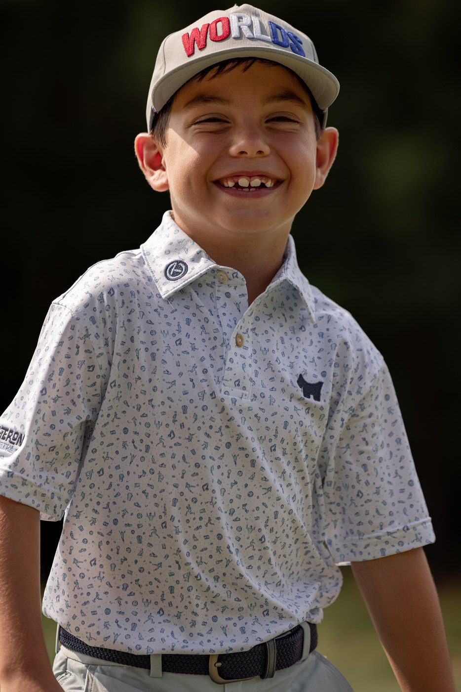 Young golfer in a Worlds cap grinning straight at the camera