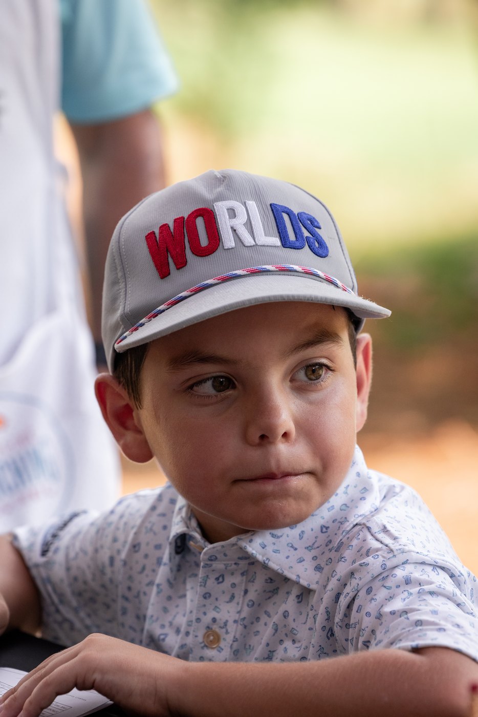 Close portrait of a young golfer in a Worlds cap, looking off camera