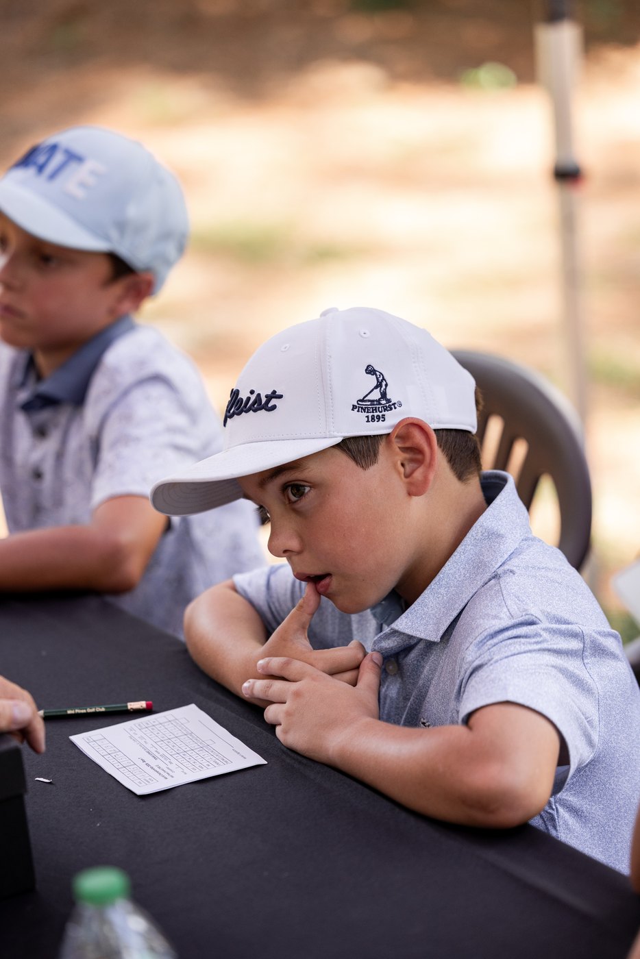Young golfer resting on the scoring table, scorecard and pencil in front of him