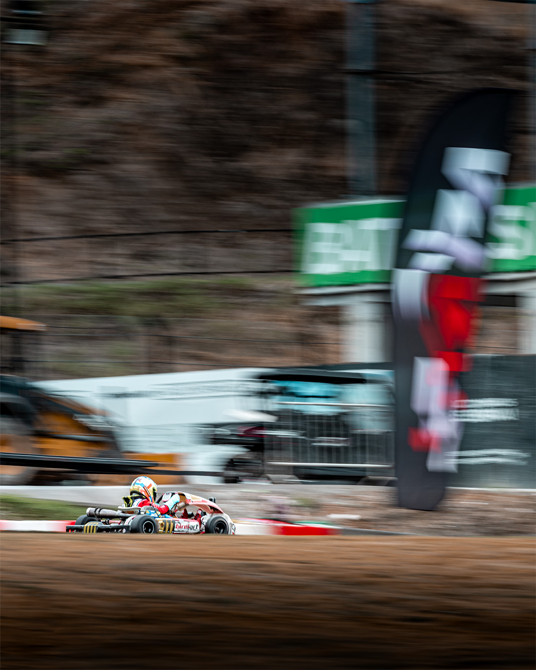 Kart blurring past trackside banners at speed